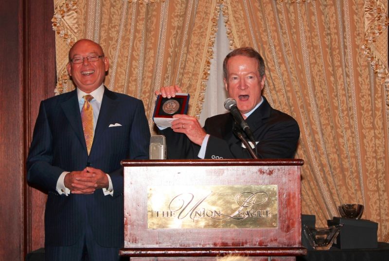 Two men in suits posing with framed medallion at Annual Members Meeting 2012